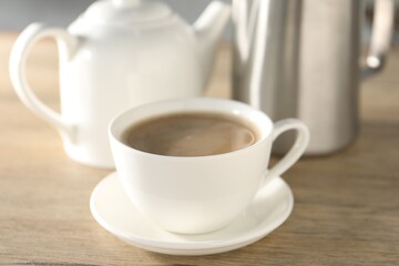 Aromatic tea with milk in cup on wooden table, closeup