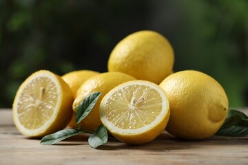 Fresh lemons and green leaves on wooden table, closeup - Powered by Adobe