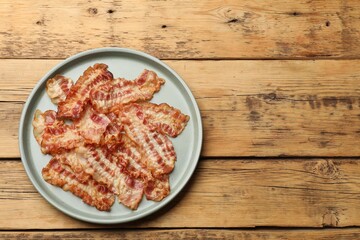 Delicious fried bacon slices on wooden table, top view. Space for text