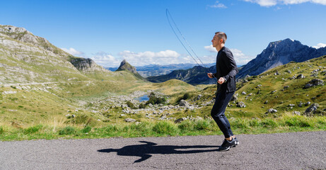 Panoramic photo of a man training on the background of a mountain landscape.