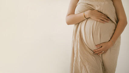 Young pregnant woman hugging her belly on white background.