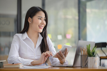 Happy asian accounting businesswoman working with calculate in office working space, Asian female employee using laptop at workplace.