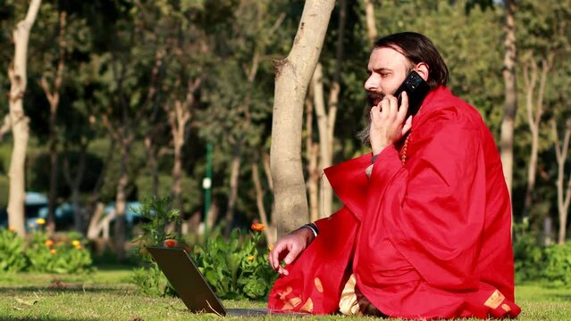 Religious saint/ astrologer talking on mobile phone video portrait outdoor in nature.