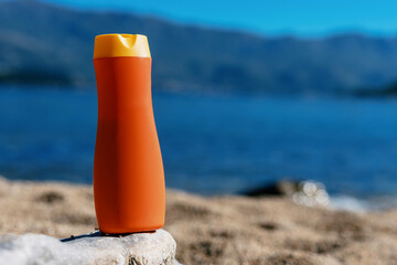 Orange jar with sunscreen on the background of the beach and the sea. Health care. Copy Space