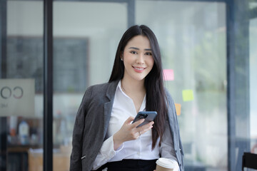 Obraz premium Happy asian Young hispanic woman using smartphone and drinking coffee at the city.