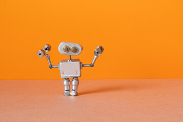 Robot athlete holds dumbbells. sports exercise fitness training. orange brown background - obrazy, fototapety, plakaty