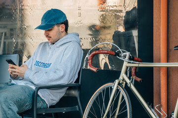 young man with vintage bicycle drinking coffee on an outdoor terrace