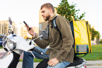 The work of a courier on a scooter in a big city. A man with a phone looks at the delivery address © makedonski2015