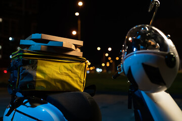 A close-up of the deliveryman's backpack lying on a scooter against the background of the evening...