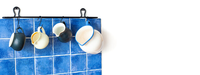 Four ceramic jugs on the background of a blue tile kitchen wall - 734861490
