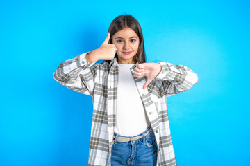 Young beautiful teen girl wearing check shirt showing thumbs up and thumbs down, difficult choose concept - obrazy, fototapety, plakaty