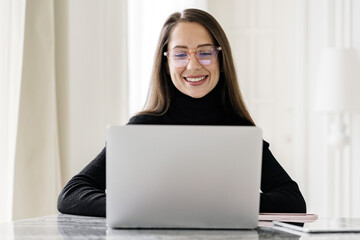 Smiling woman working on laptop at home, enjoying remote work.