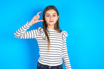 Fototapeta premium Young beautiful teen girl wearing striped T-shirt smiling and confident gesturing with hand doing small size sign with fingers looking and the camera. Measure concept