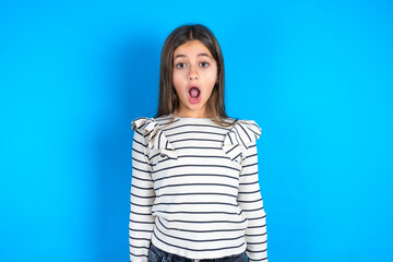 Oh my God. Surprised Young beautiful teen girl wearing striped T-shirt stares at camera with...
