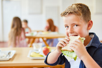 Boy eating fresh sandwich at school cafeteria