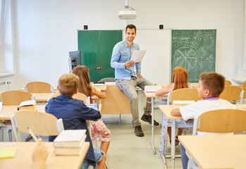 Teacher conducting lecture with kids sitting on bench