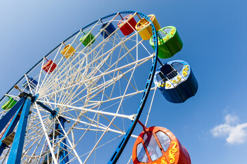 Carousel "Ferris Wheel" against a blue clear sky. Place for inscription.