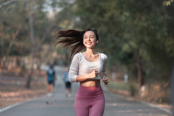 Smiling women brunette enjoys a summer run on a park path