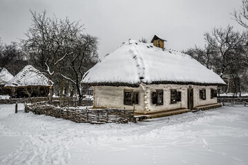 Old house with straw roof in winter village