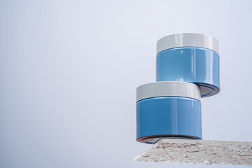 Face cream stands on a glass shelf. Blue jar with moisturizer. Anti-aging cosmetics