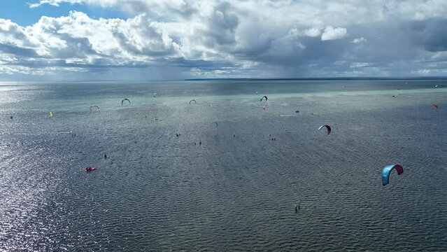 People swim in the sea on a kiteboard or kitesurfing. Summer sport learning how to kitesurf. Kite surfing on Puck bay in Jastarnia, Poland, Europe aerial drone photo view