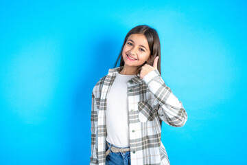 Beautiful kid girl wearing plaid shirt doing happy thumbs up gesture with hand. Approving expression looking at the camera showing success.