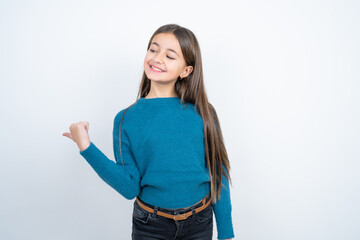 Charming beautiful kid girl wearing blue sweater looking at copy space having advertisements