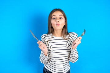 hungry Beautiful kid girl wearing striped T-shirt holding in hand fork knife want tasty yummy pizza...