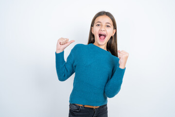 Ecstatic beautiful kid girl wearing blue sweater shout loud yeah fist up raise win lottery