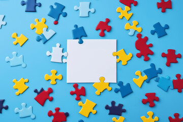 Naklejka premium World Autism Awareness Day or month concept. Creative design for April 2. Blue, red, yellow jigsaw puzzles, symbol of awareness for autism spectrum disorder on blue background. Top view, copy space