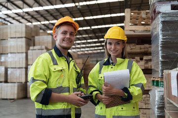 Male and female warehouse worker working in lumber storage warehouse. Workers working in timber...