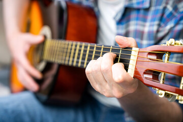 Hands of a young man playing the guitar. Close-up. Selective focus.