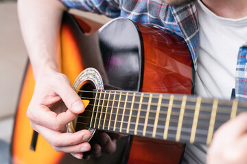Hands of a young man with mediator playing on guitar strings. Close-up. Selective focus.