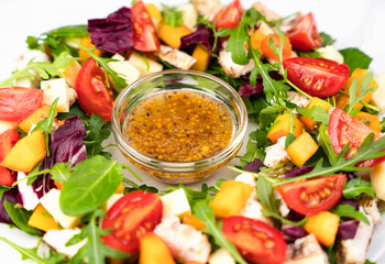 Tasty and healthy salad from chicken, vegetables, lettuce and arugula leaves with honey mustard sauce. Close-up. Top view. Selective focus.
