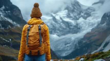 In a yellow jacket and backpack, a woman travels through the mountains