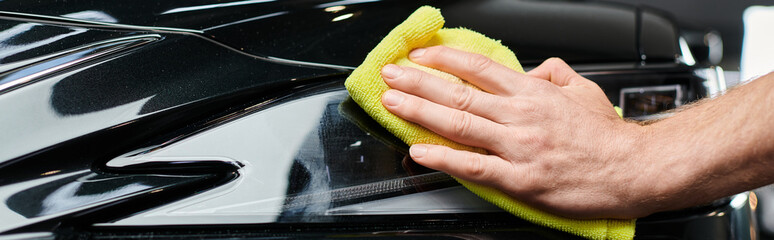 cropped view of professional dedicated serviceman using rag to clean black modern car, banner