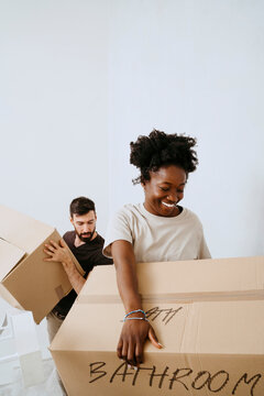 Multiracial couple carrying cardboard boxes at home