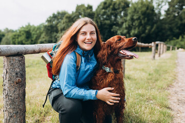 Happy 30s Girl loving and hugging tightly her dog. Travel and hiking with pet. Redhead Woman in...