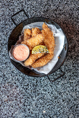 golden deep-fried battered chicken nuggets.succulent chicken chunks ensconced in a delectable batter, crisped up with Panko, and draped in sauce closeup on the plate on the table.