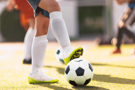 Soccer player practicing dribbling with friends in a team. Group of school teenagers kicking soccer balls during a training session. Boys in football club in cleats improving ball possession skills