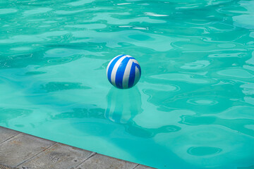 Blue and white plastic ball floating in the swimming pool