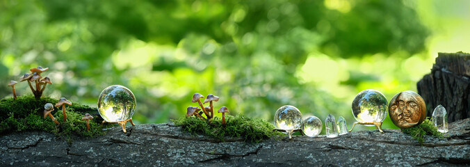 Quartz crystal balls and moon amulet on tree trunk in forest, abstract natural background. esoteric...