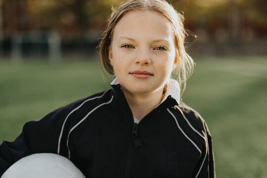 Portrait of elementary girl with soccer ball in sports field