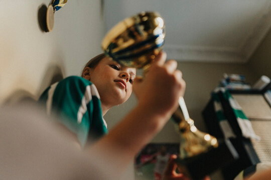 Dedicated girl holding trophy while sitting at home