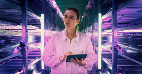 Portrait of Female Agricultural Engineer Walking in Vertical Farm Facility Next to Racks with Fresh...