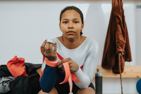 Portrait of teenage female athlete sitting in locker room