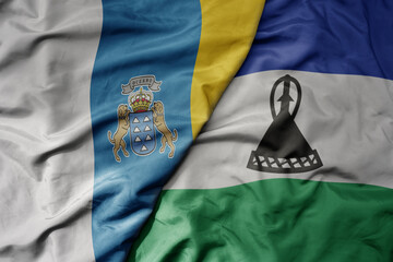 big waving national colorful flag of lesotho and national flag of canary islands .