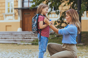 Mother accompanies the child to school. Mom supports and motivates the student.caring mother gently kisses her daughter on the forehead. 