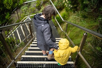 toddler and baby walking down stairs in a national park on wet slippers steps in australia