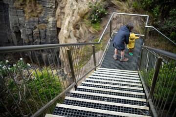 toddler and baby walking down stairs in a national park on wet slippers steps in australia